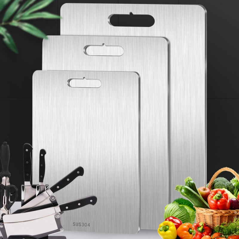 Three stainless steel cutting boards in different sizes beside fresh vegetables